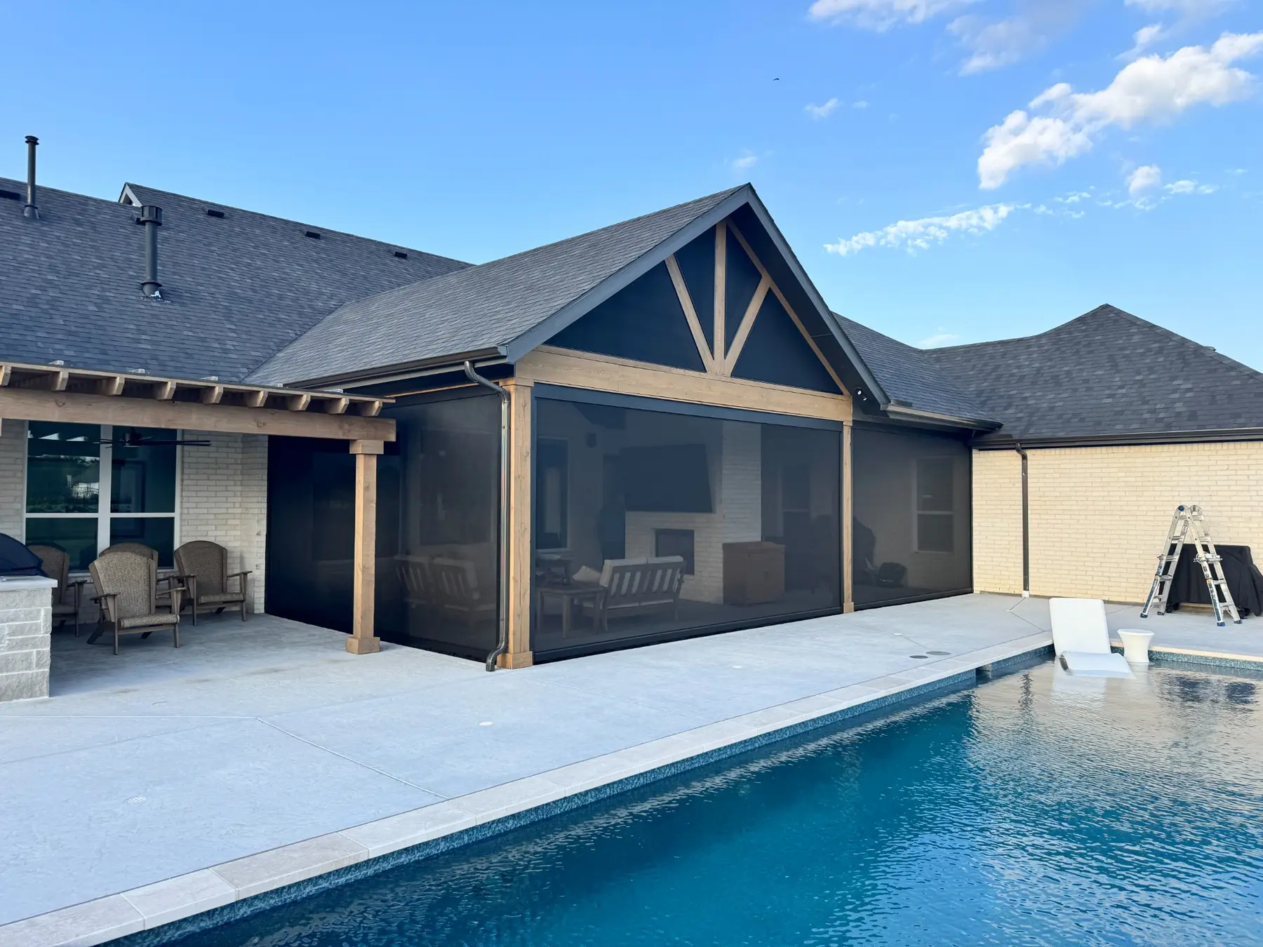 Poolside patio with multiple finished motorized screens and an installation ladder nearby.