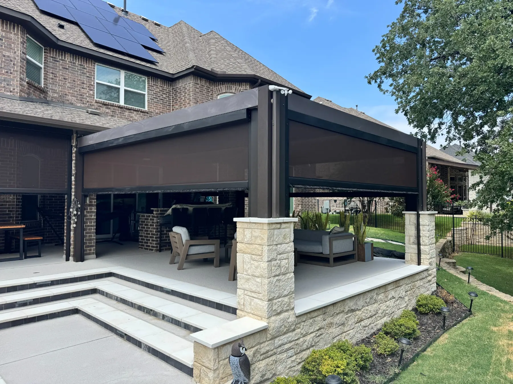 Dark motorized screens partially lowered around a freestanding poolside patio pavilion.