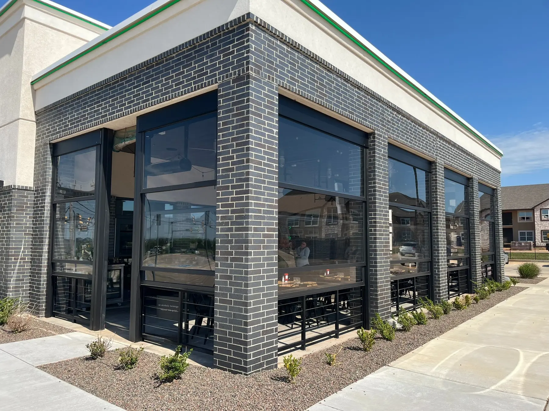 Clear STAX motorized lift-wall panels installed around a brick restaurant patio.