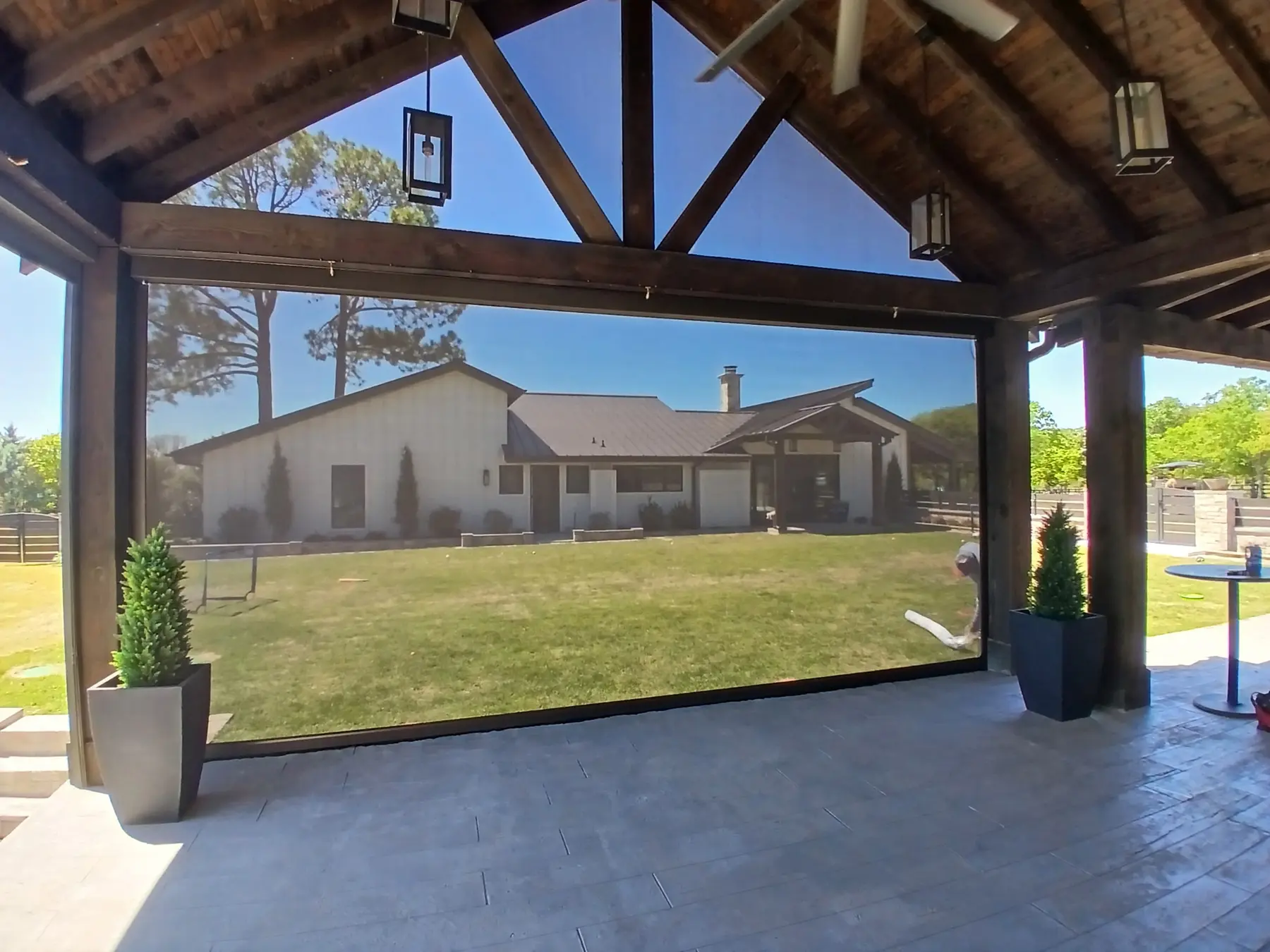 View through a large patio screen from beneath a timber-framed covered patio.